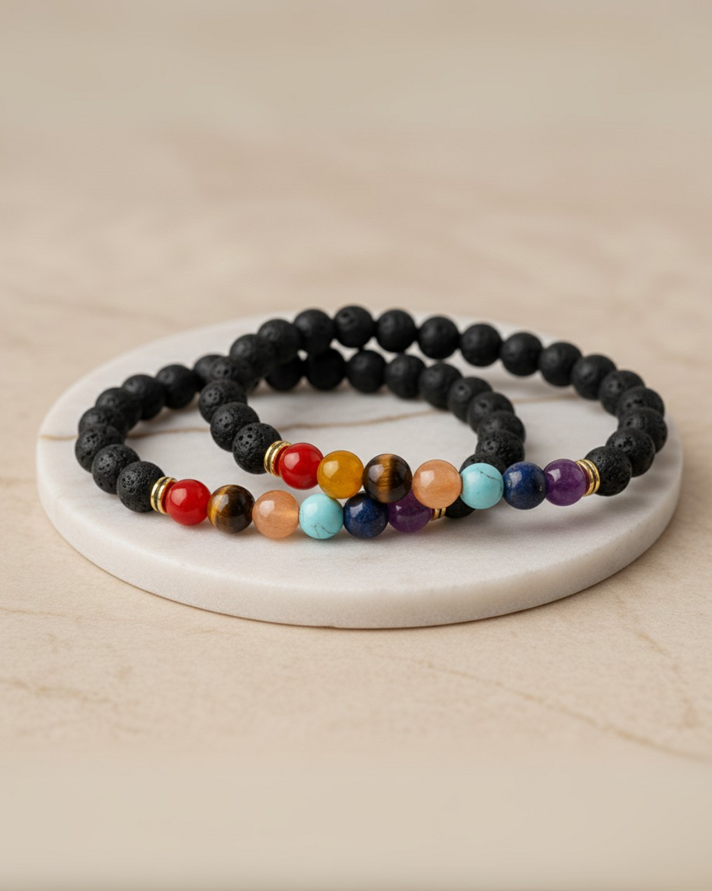 Set of two beaded 7 chakra bracelets on a white marble coaster with a beige background