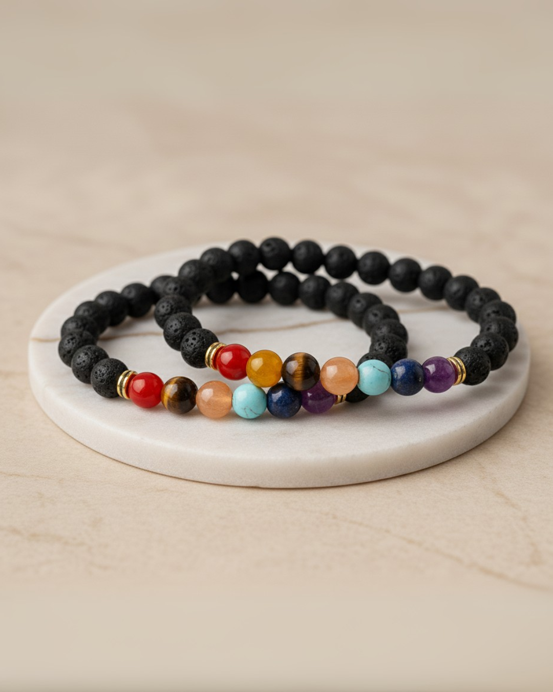 Set of two beaded 7 chakra bracelets on a white marble coaster with a beige background