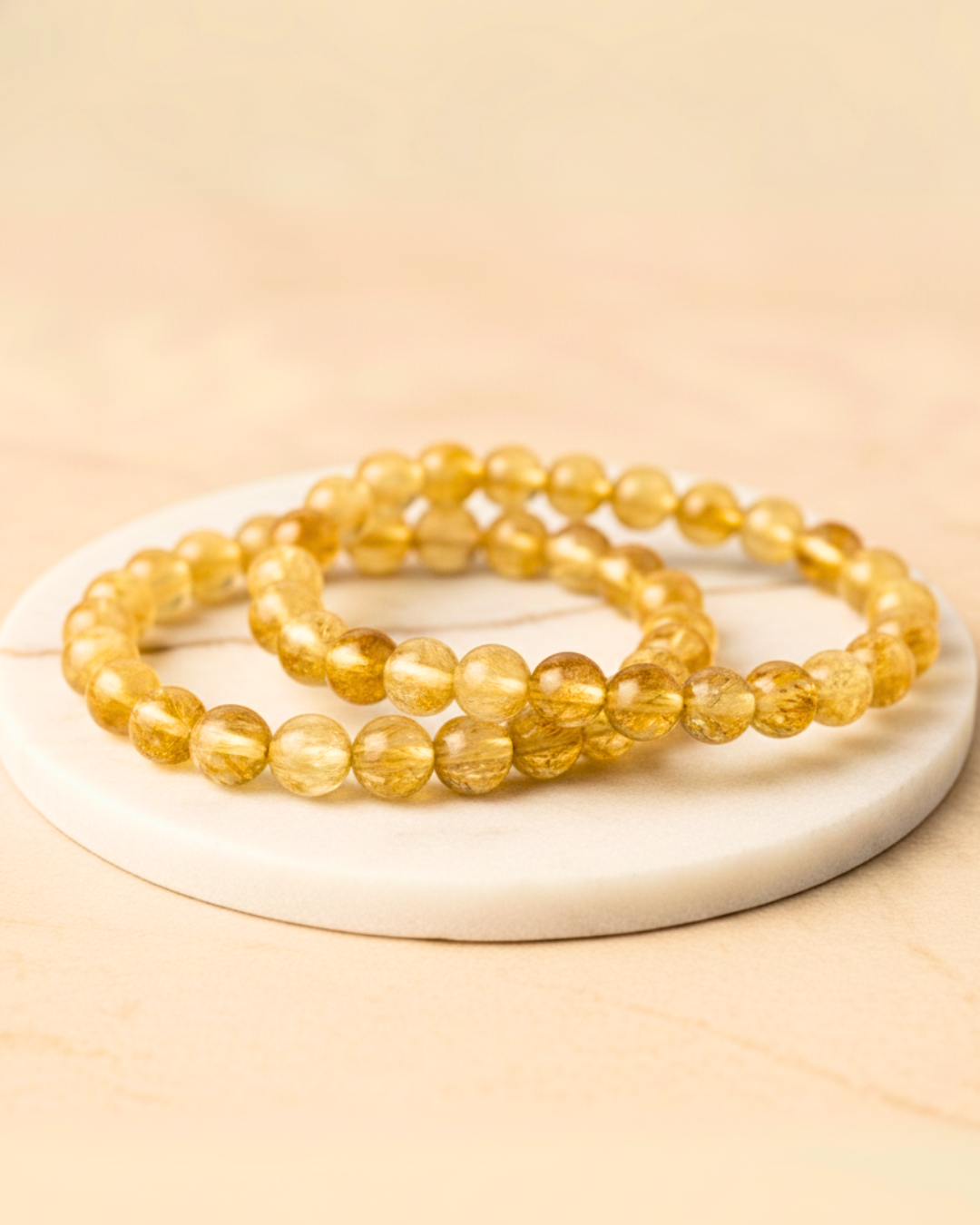 Set of yellow beaded Citrine bracelets 8mm on a white plate with a beige background