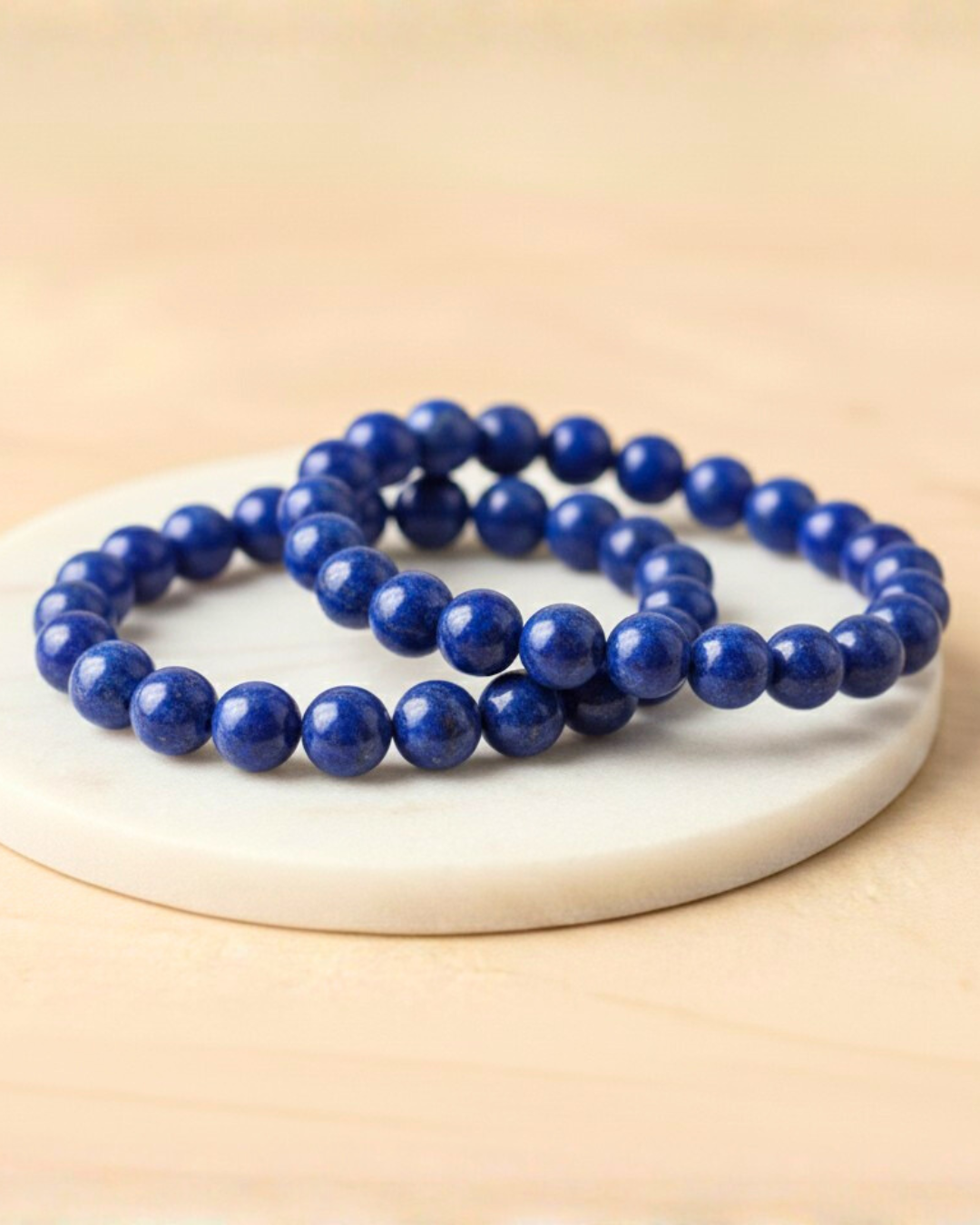 Blue beaded Lapis 8mm bracelet on a white plate with a beige background