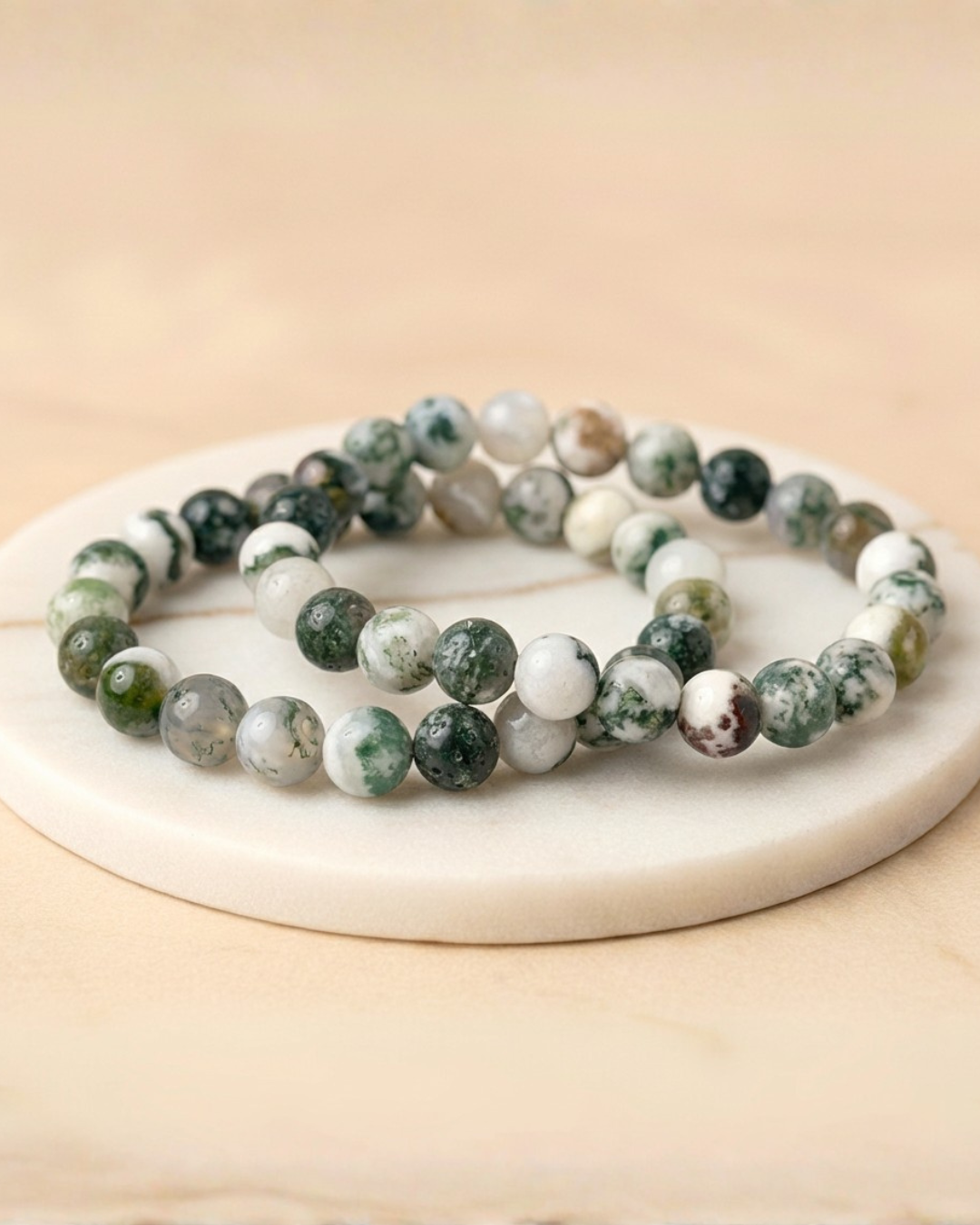 Set of green and white beaded Tree Agate Bracelets 8mm on a beige surface