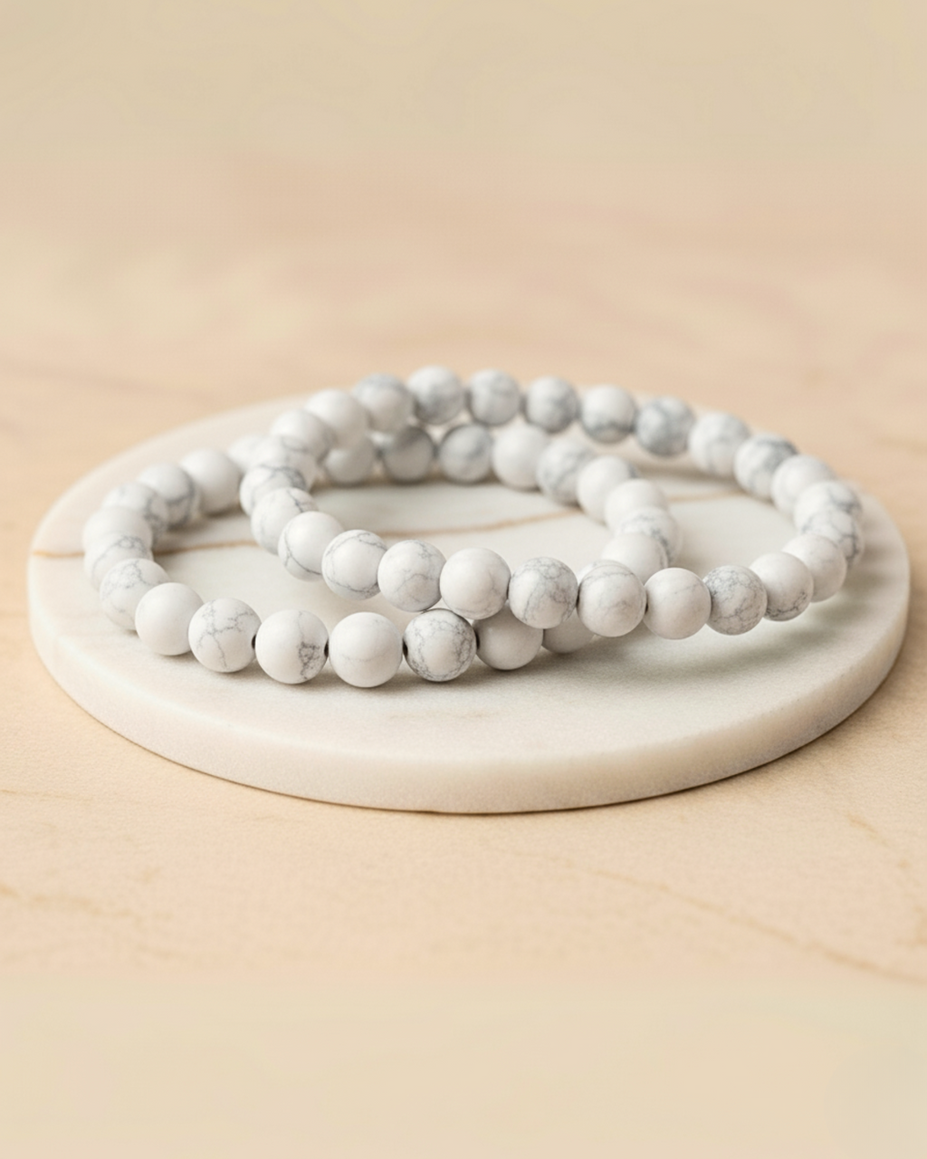 Three white beaded bracelets on a round stone surface with a beige background. Howlite Bracelet 8mm.